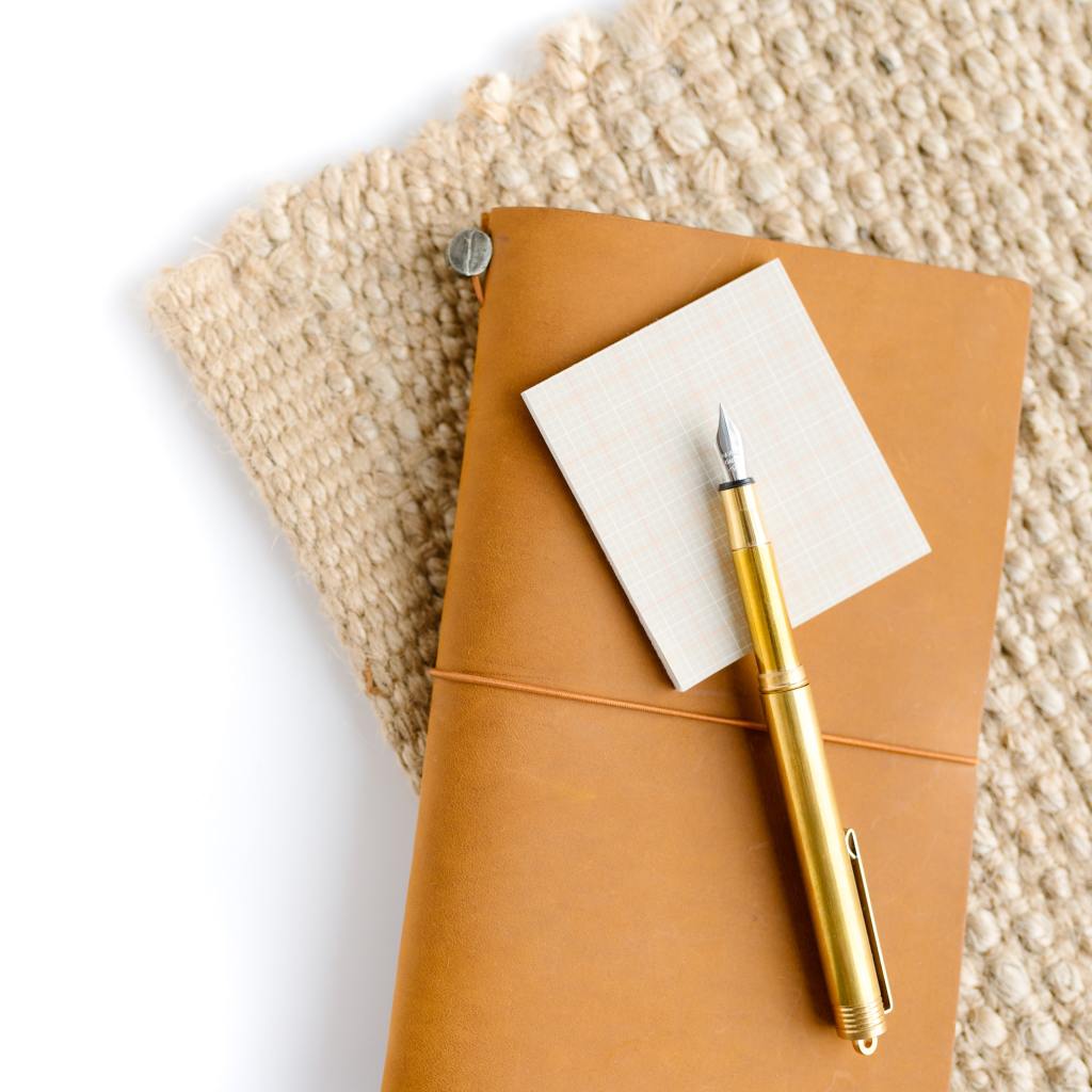 Neutral color notebook with post it note and pencil
